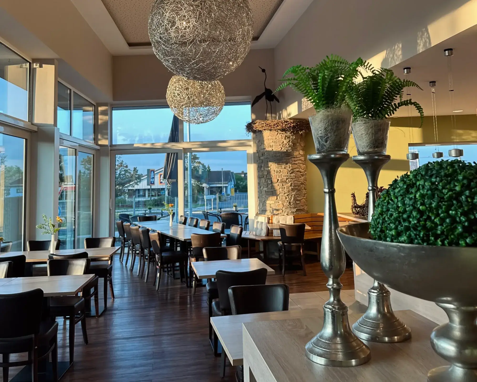 Lichtdurchfluteter Cafébereich mit großen Fenstern, Kugelleuchten und Blick auf die Terrasse in der Bäckerei Storch am Dicken Turm