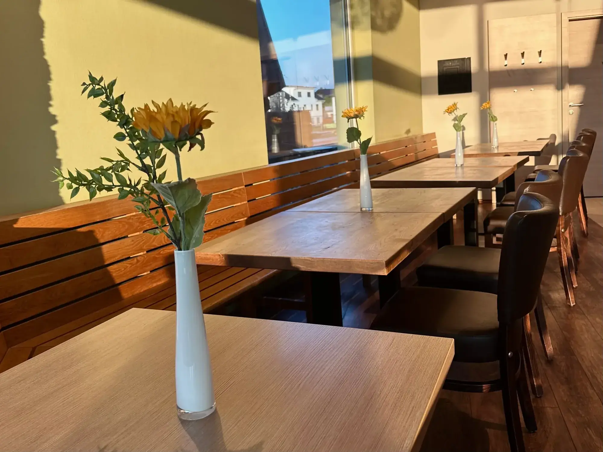 Holzbänke und Tische mit Sonnenblumen im Gastraum der Bäckerei Storch am Dicken Turm
