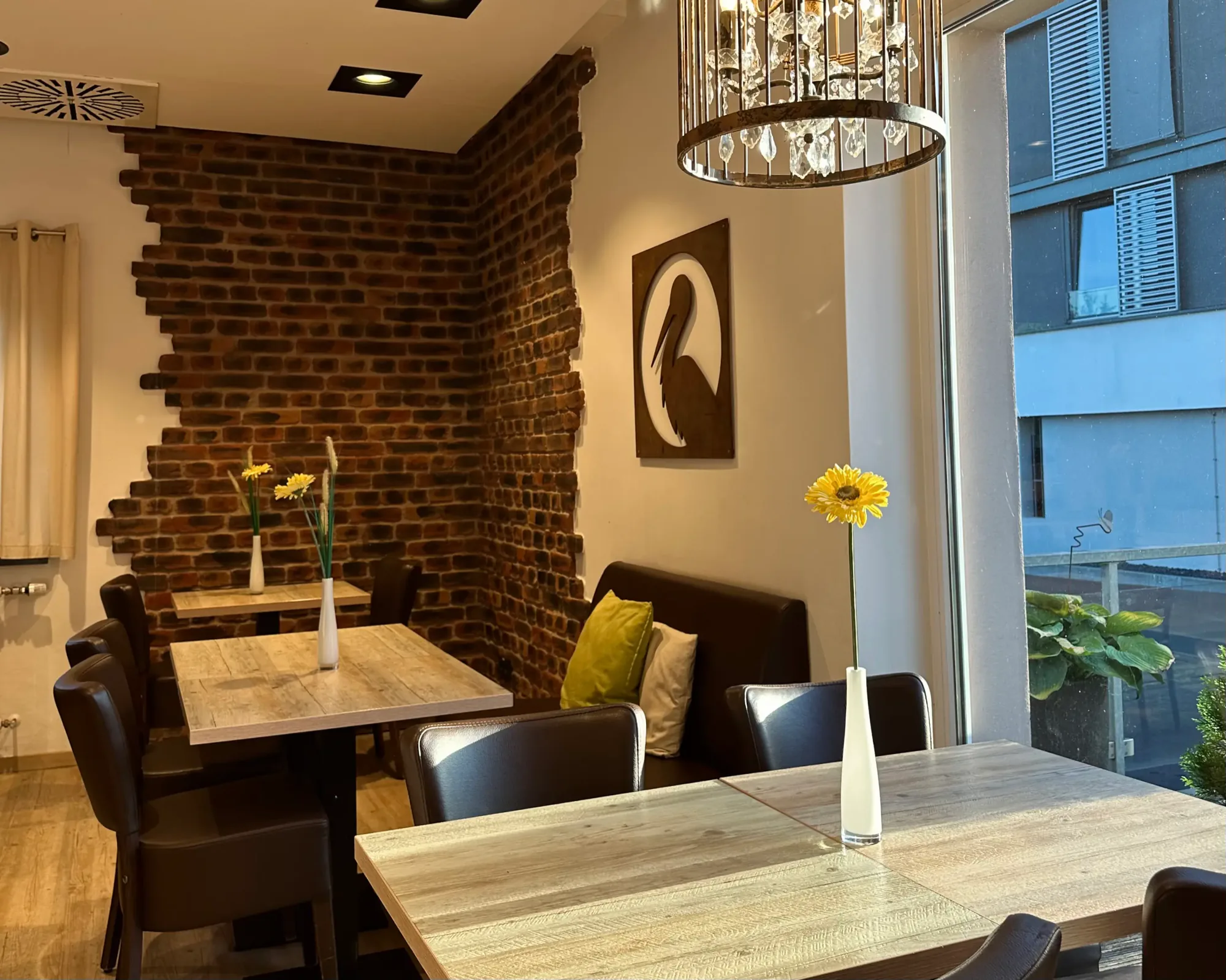 Cafébereich mit Backsteinwand, Sitzbank und Kronleuchter in der Bäckerei Storch in Petersberg