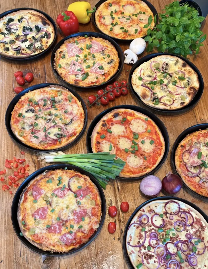 Verschiedene frisch gebackene Pizzen mit Gemüse, Salami und Schinken