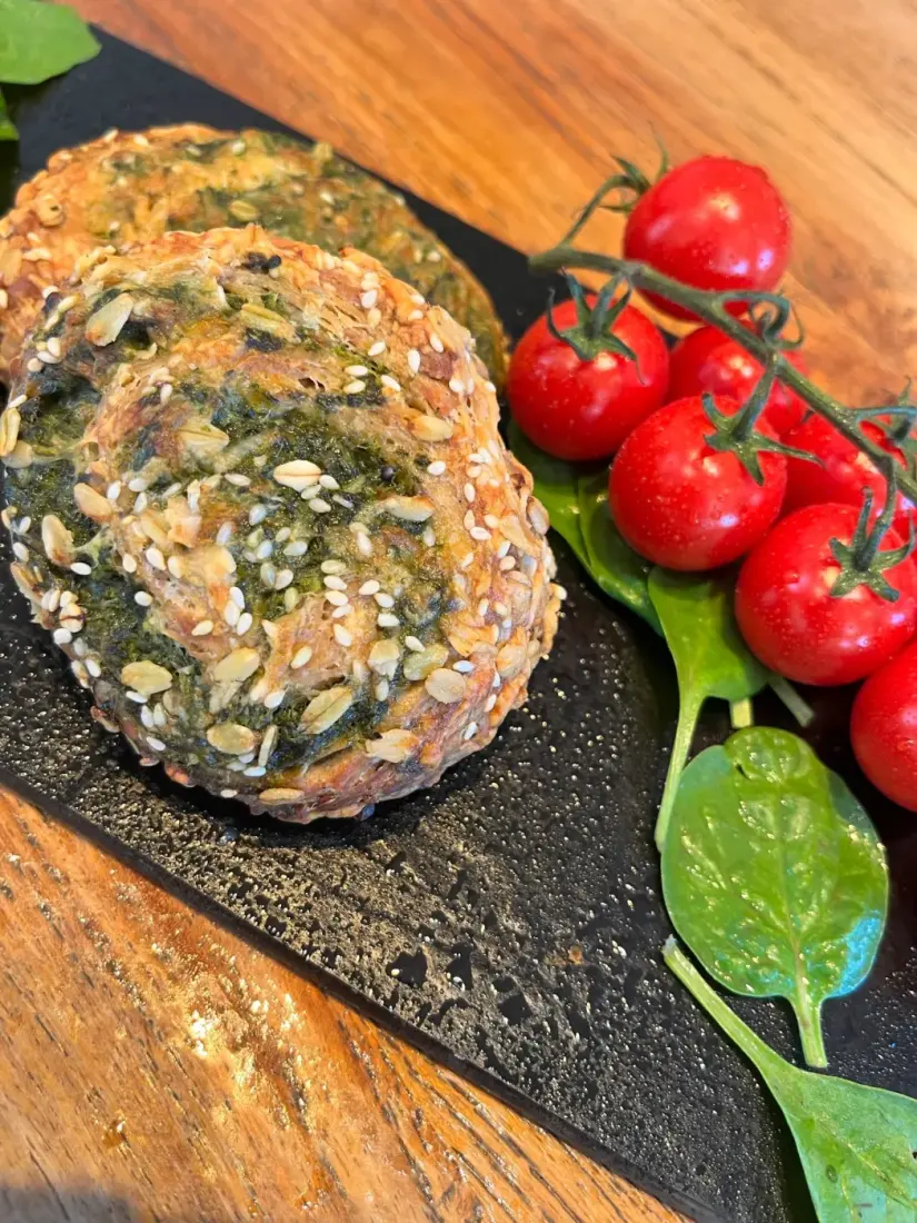 Herzhafte Körnerbrötchen mit Spinat neben frischen Tomaten